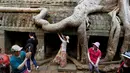 Wisatawan berpose saat mengunjungi kompleks kuil Ta Prohm di provinsi Siem Reap, Kamboja. Kuil yang semakin populer semenjak digunakan untuk lokasi syuting film Tomb Raider tersebut memiliki nilai sejarah tinggi dan masih terjaga keasliannya. (REUTERS/Samrang Pring)