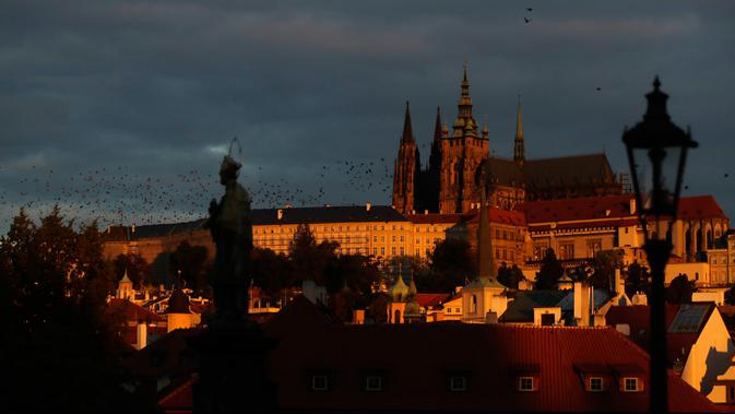 Sekawanan burung terbang melewati Kastil Praha saat matahari terbit di Praha, Republik Ceko, Kamis (8/10/2020). Infeksi virus corona COVID-19 di Ceko mencapai rekor tertinggi baru dua hari berturut-turut, melampaui 5.000 kasus dalam sehari untuk pertama kalinya. (AP Photo/Petr David Josek)