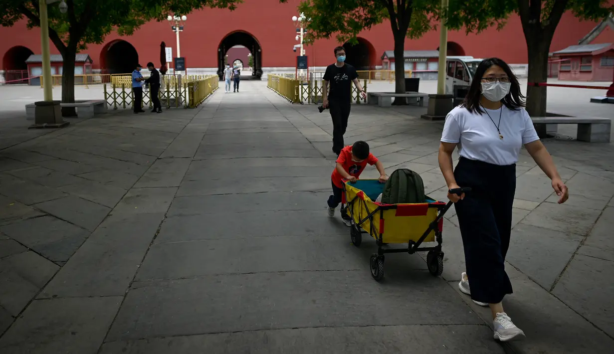 Seorang perempuan menarik gerobak portabel dengan seorang anak mendorong ke belakang ketika bersiap untuk mengunjungi Kota Terlarang di Beijing, China, Selasa (7/6/2022). Pemerintah melonggarkan beberapa pembatasan Covid-19 dengan sebagian besar museum gedung bioskop, dan pusat kebugaran diizinkan beroperasi hingga 75 persen dari kapasitas. (WANG Zhao / AFP)