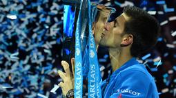 Novak Djokovic mencium trofi juara turnamen tenis ATP World Tour Finals di London, Inggris, (22/11/2015). (AFP Photo/Glyn Kirk)