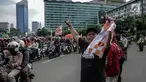Warga berswafoto dengan latar belakang suporter Persija Jakarta, Jakmania, yang melakukan pawai kemenangan Juara Piala Presiden di kawasan Bundaran HI, Minggu (18/2). Lautan oranye memenuhi jalan-jalan di ibu kota. (Liputan6.com/Faizal Fanani)