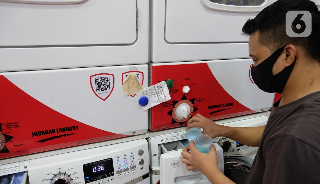 Pekerja menuangkan pewangi ke dalam mesin cuci di gerai jasa layanan laundry, kawasan Kemang, Jakarta, Rabu (25/11/2020). Banyaknya pekerja yang kembali bekerja di kantor dan memasuki musim hujan diprediksi akan meningkatkan omset jasa laundry yang cukup signifikan. (Liputan6.com/Herman Zakharia)
