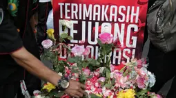 Pengunjung car free day meletakan bunga yang diberikan oleh anggota TKN Milenial Jokowi-Ma'ruf dalam kegiatan tabur bunga di Bundaran HI, Jakarta, Minggu (28/4/2019). Aksi tersebut sebagai bentuk duka atas meninggalnya 272 petugas KPPS dalam Pemilu 2019. (Liputan6.com/Faizal Fanani)
