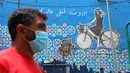 Seorang pria berjalan melewati sebuah grafiti yang mendorong kegiatan bersepeda di Beirut, Lebanon (11/6/2020). Belakangan ini, kegiatan bersepeda menjadi aktivitas yang lazim di Lebanon sejak pemerintah memberlakukan pembatasan guna meredam pandemi COVID-19. (Xinhua/Bilal Jawich)