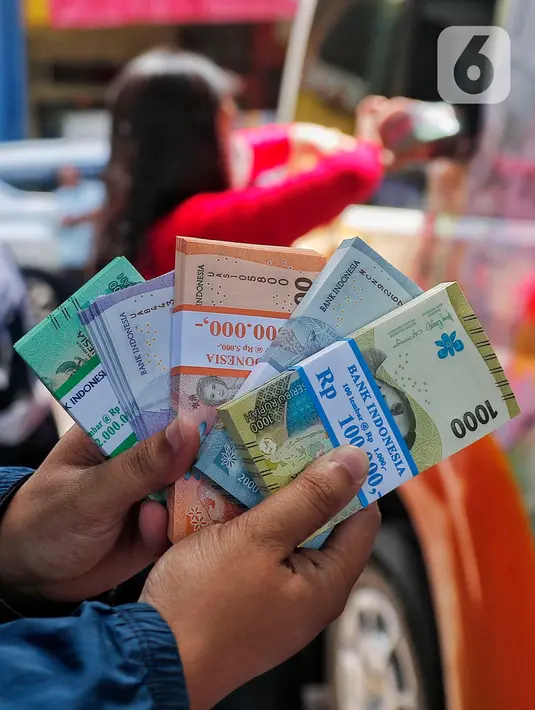Warga memperlihatkan pecahan uang tunai baru di layanan kas keliling Bank Indonesia di Pasar Kopro, Jakarta Barat, Rabu (29/3/2023). (Liputan6.com/Angga Yuniar)