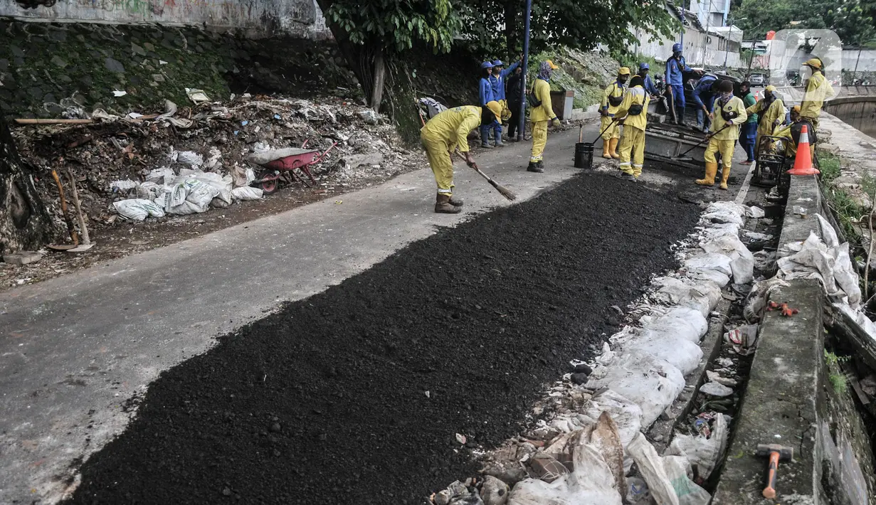 Petugas Sudin Bina Marga Jakarta Pusat memperbaiki jalan ambles di Jalan Inspeksi Kali Ciliwung, Kenari, Rabu (19/1/2022). Jalan yang berada di belakang RSCM tersebut ambles sepanjang 40 meter akibat terkikis oleh hujan deras kemarin sehingga menyulitkan akses warga. (merdeka.com/Iqbal S Nugroho)