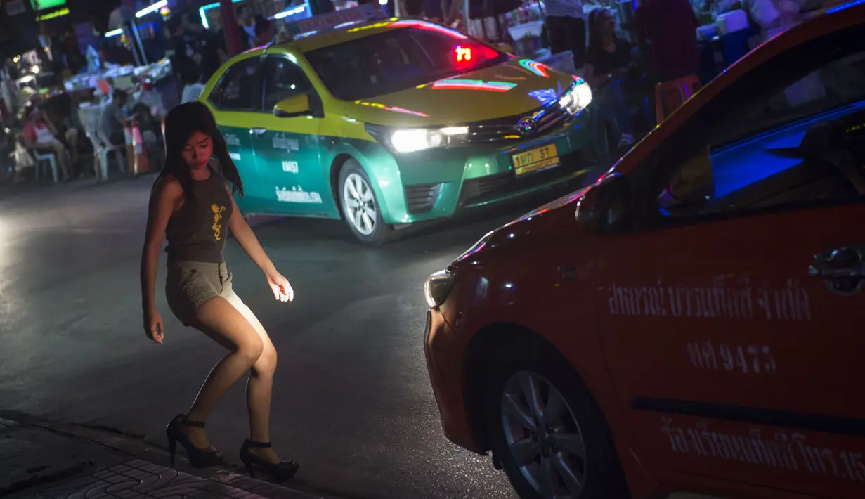 Foto pada 11 Oktober 2018 menunjukkan seorang wanita menyebrang jalan di Nana Red Light Distrik, Bangkok, Thailand. Nana Red Light District memang dikenal sebagai kawasan hiburan malam terbesar di Bangkok. (Romeo GACAD / AFP)