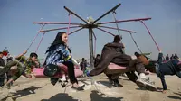 Anak-anak bermain ayunan selama perayaan Nowruz, Tahun Baru Persia, di Kabul, Afghanistan, (21/3). Nowruz dirayakan pada hari pertama musim semi di negara-negara termasuk Afghanistan, Tajikistan, dan Iran. (AP Photo/Rahmat Gul)