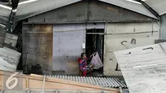 Seorang nenek duduk sambil memomong bayi menunggu jatah pembongkaran di kolong tol Pluit, Jakarta, Rabu (2/3). Pemprov DKI membongkar 385 bangunan di kawasan tersebut berdasarkan Perda No 8 Tahun 2007 tentang ketertiban umum. (Liputan6.com/Yoppy Renato)