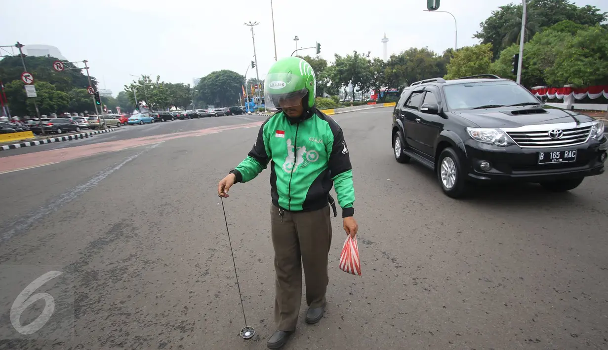 Pengendara Gojek bernama Ari mencari ranjau paku yang berserakan di sekitar Istana Negara, Jakarta, Minggu (14/8). Pria 32 tahun tersebut secara ikhlas mengumpulkan ranjau paku di sekitar Istana Negara.(Liputan6.com/Immanuel Antonius)