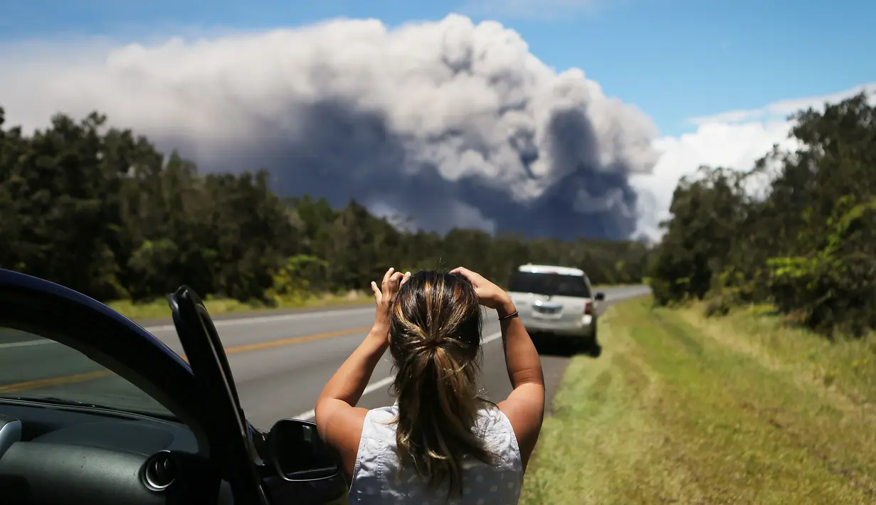 Seorang wanita berada di mobilnya mengambil gambar kepulan abu vulkanik dari gunung berapi Kilauea di Big Island Hawaii (15/5). (Mario Tama/Getty Images/AFP)