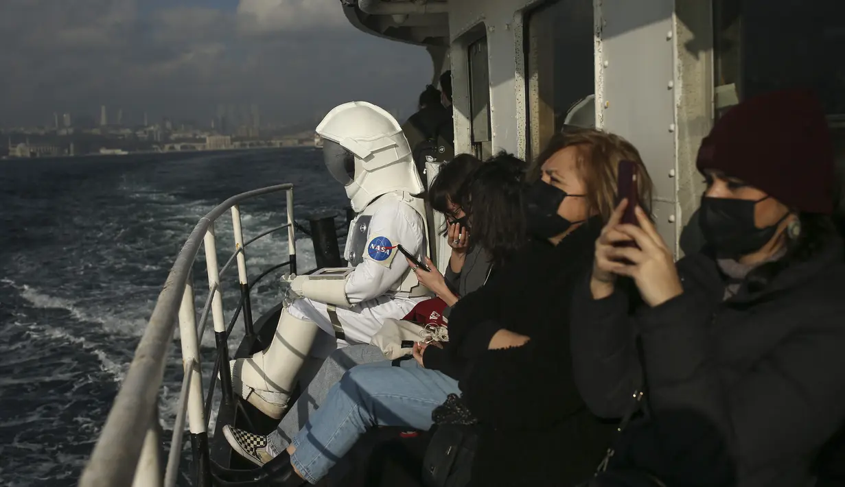 Seorang pria berpakaian astronaut melintasi Bosphorus dengan kapal feri sebagai bagian dari kampanye untuk mempromosikan Pameran Luar Angkasa NASA di Istanbul, Turki, pada 5 Desember 2021. Pameran tersebut akan dibuka untuk umum bulan ini. (AP Photo/Emrah Gurel)
