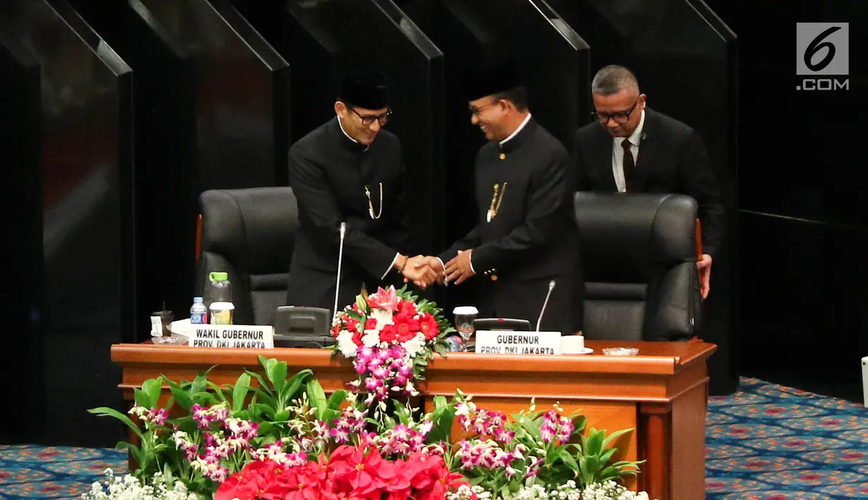 Gubernur dan Wakil Gubernur DKI Jakarta Anies Baswedan (tengah) dan Sandiaga Uno (kiri) bersalaman dalam rapat istimewa bersama DPRD Provinsi DKI Jakarta, Jumat (22/6). Pemprov DKI mengangkat tema 'Adil, Maju, Bahagia'. (Liputan6.com/Immanuel Antonius)