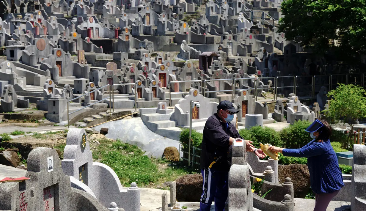 Sepasang suami istri membakar uang kertas di makam kerabat saat Festival Ching Ming atau Hari Sapu Makam di Hong Kong, Selasa (5/4/2022). Ribuan warga Hong Kong memberi hormat kepada leluhur dan kerabat mereka selama festival tahunan ini. (AP Photo/Vincent Yu)