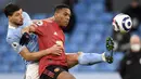 Striker Manchester United, Anthony Martial (kanan) berebut bola dengan bek Manchester City, Ruben Dias dalam laga lanjutan Liga Inggris 2020/21 di Etihad Stadium, Minggu (7/3/2021). MU menang 2-0 atas Mancity. (AFP/Peter Powell/Pool)