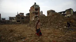 Seorang warga berjalan melewati runtuhan banguan yang rusak akibat gempa di Bhaktapur, Nepal (14/7/2015). PBB melaporkan dua bulan setelah gempa di Nepal, warga masih sulit mendapatkan makanan dan perawatan kesehatan. (REUTERS/Navesh Chitrakar)