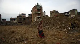 Seorang warga berjalan melewati runtuhan banguan yang rusak akibat gempa di Bhaktapur, Nepal (14/7/2015). PBB melaporkan dua bulan setelah gempa di Nepal, warga masih sulit mendapatkan makanan dan perawatan kesehatan. (REUTERS/Navesh Chitrakar)