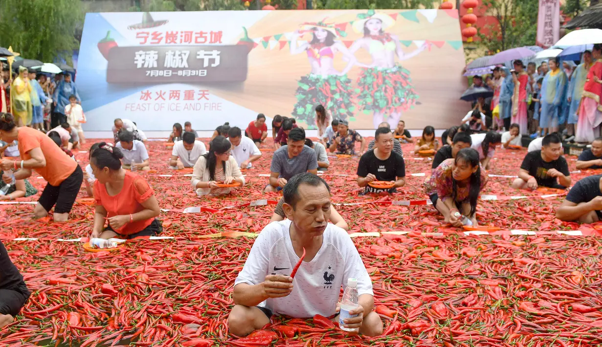 Sejumlah kontestan memakan cabai saat mengambil bagian dalam kompetisi makan cabai di Ningxiang di provinsi Hunan tengah, China (8/7). Pemenang dalam kontes ini telah memakan 5 cabai dalam waktu satu menit. (AFP Photo)