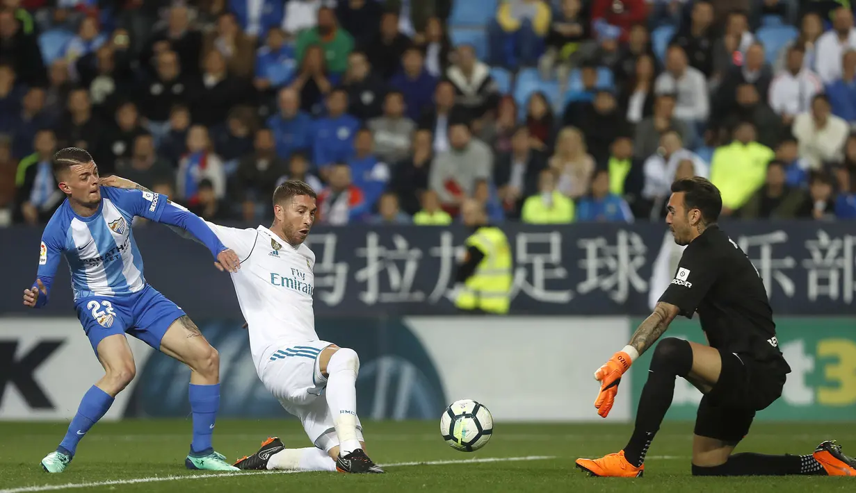 Pemain Real Madrid, Sergio Ramos (tengah) berusaha menghalau bola dari kejaran pemain Malaga, Maxime Lestienne (kiri) pada lanjutan La Liga Santander di Rosaleda stadium, Malaga, (15/4/2018). Madrid menang 2-1. (AP/Miguel Morenatti)