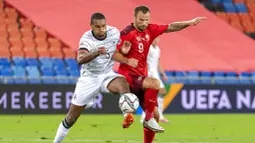 Pemain Jerman, Jonathan Tah, berebut bola dengan pemain Swiss, Haris Seferovic, pada laga UEFA Nations League di Stadion St. Jakob-Park, Senin, (7/9/2020). Kedua tim bermain imbang 1-1. (Georgios KefalasKeystone via AP)