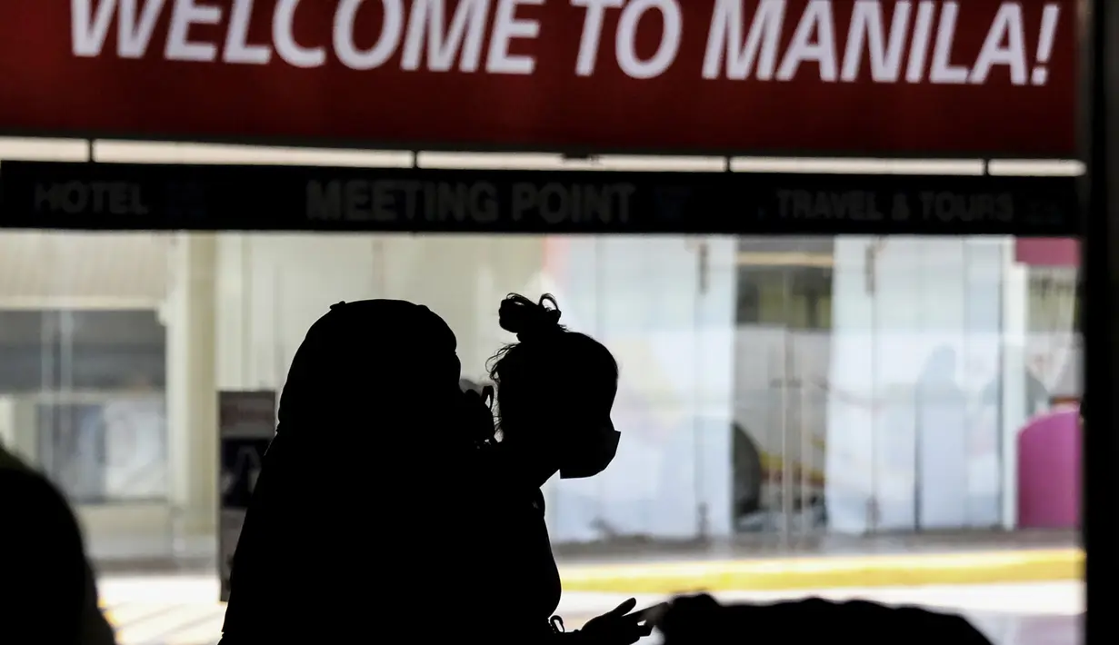 Seorang penumpang asing yang mengenakan masker tiba di Bandara Internasional Manila, Filipina, Kamis (10/2/2022). Filipina mulai hari ini membuka kembali pintu bagi turis asing yang telah divaksinasi penuh Covid-19 setelah hampir dua tahun menutup perbatasannya. (AP Photo/Basilio Sepe)