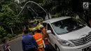 Sebuah mobil tertimpah lampu jalanan di kawasan jalan purworejo Menteng, Jakarta, Senin (27/11). Akibat hujan deras dan angin kencang sebuah pohon tumbang dan lampu jalan mengenai mobil Alphard putih yang terparkir. (Liputan6.com/Faizal Fanani)