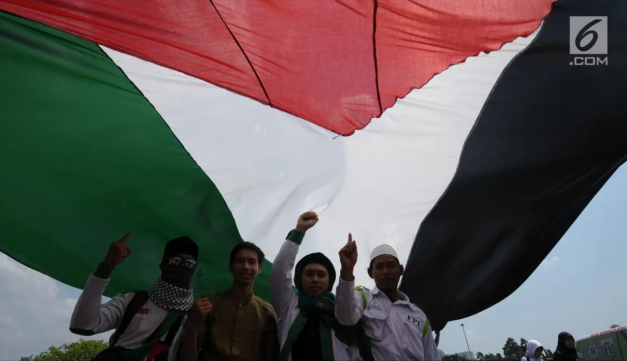 Peserta aksi membentangkan bendera Palestina di Lapangan Monumen Nasional, Jakarta, Jumat (11/5). Aksi ini untuk menyoroti konflik Palestina dan Israel pada perebutan bangunan suci atau Baitul Maqdis di kota Yerussalem. (Liputan6.com/Helmi Fithriansyah)