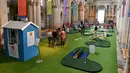 Orang-orang bermain di lapangan golf kecil yang didirikan  di dalam Katedral Rochester, Inggris pada 6 Agustus 2019. Lapangan golf ini membentang di sepanjang lorong dan memiliki sembilan lubang dengan miniatur jembatan.  (Ben STANSALL / AFP)