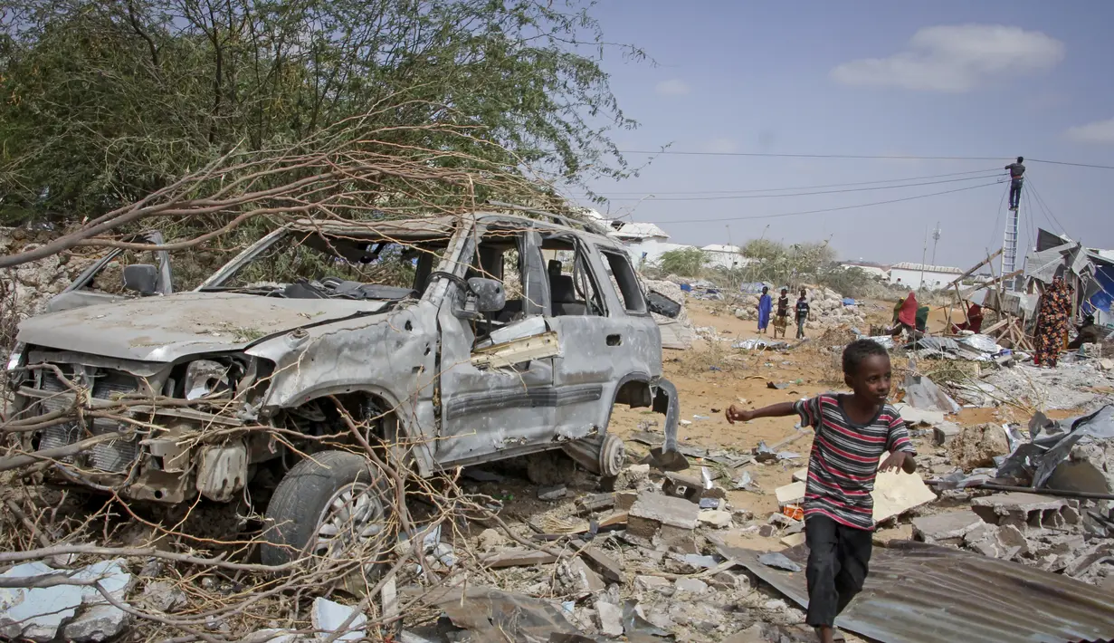Seorang anak laki-laki berlari melewati puing-puing kendaraan yang hancur dalam serangan terhadap polisi dan pos pemeriksaan di pinggiran ibu kota Mogadishu, Somalia (16/2/2022). Serangan oleh kelompok ekstremis al-Shabab menewaskan lima orang dan melukai 16 orang. (AP Photo/Farah Abdi Warsameh)