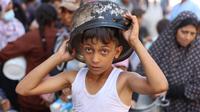 Seorang anak laki-laki Palestina mengantri untuk menerima jatah makanan, yang ditawarkan oleh sebuah badan amal, di kamp pengungsi Al-Shati di Gaza pada 17 Oktober 2024. (Omar AL-QATTAA/AFP)