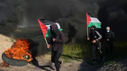 Demonstran berlari sambil mengibarkan bendera nasional mereka sementara yang lain membakar ban saat protes terhadap serangan militer Israel ke Kota Nablus, Tepi Barat, di sepanjang pagar perbatasan dengan Israel di sebelah timur Kota Gaza, 22 Februari 2023. Para pejabat Palestina mengatakan sejumlah warga Palestina telah terbunuh dan lebih dari seratus orang terluka dalam serangan tentara Israel yang jarang terjadi di Tepi Barat. (AP Photo/Adel Hana)