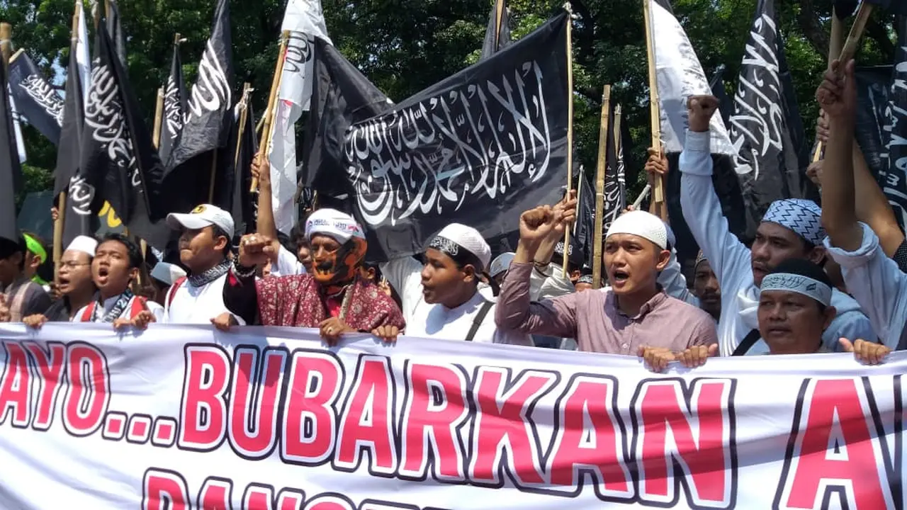 Sejumlah massa membawa bendera dengan tulisan kalimat tauhid di Jalan Medan Merdeka. (Liputan6.com/Ika Defianti)