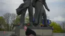 <p>Seorang perempuan berpose untuk foto sambil duduk di atas kepala patung pekerja Soviet selama pembongkaran monumen era Soviet untuk persahabatan antara Rusia dan Ukraina, di tengah invasi Moskow di Kiev tengah, Ukraina, Selasa (26/4/2022). Patung itu terletak di bawah 'Lengkungan Persahabatan Rakyat' titanium raksasa, yang didirikan pada 1982 untuk memperingati ulang tahun ke-60 Uni Soviet. (AP Photo/Efrem Lukatsky)</p>