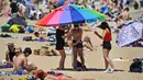 Sejumlah wanita memasang payung saat menikmati cuaca hangat di Pantai St Kilda Melbourne, Australia (3/11/2020). Negara bagian Victoria di Australia mencatat nol kasus penularan COVID-19 selama empat hari berturut-turut setelah berjuang melawan gelombang kedua wabah pandemi. (AFP/William West)