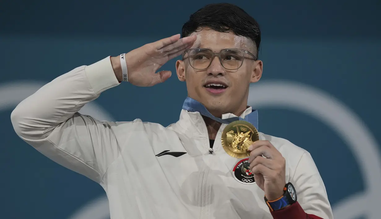 <p>Tampil di urutan terakhir dari total 29 atlet Indonesia yang berlaga di Olimpiade Paris 2024, Rizki Juniansyah betul-betul menjadi penutup yang manis bagi kontingen Indonesia. Atlet berusia 21 tahun itu sukses menyumbang medali emas kedua untuk Indonesia dai kelas 73 kg putra cabor angkat besi yang berlangsung di Paris Expo Porte de Versailles, Paris, Jumat (9/8/2024) dini hari WIB. Rizki mampu mengangkat total 354 kg yang menjadi rekor baru Olimpiade dengan rincian 155 kg pada angkatan snatch dan 199 kg untuk clean and jerk. (AP Photo/Kin Cheung)</p>