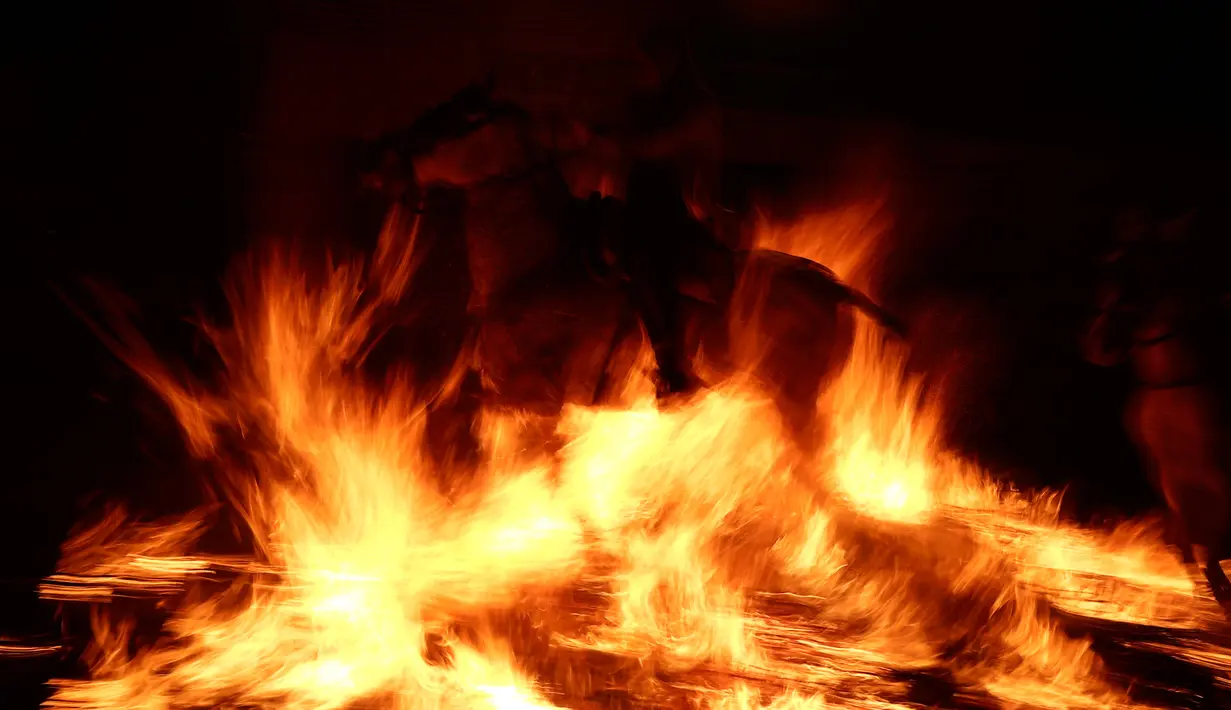 Seorang pria menunggangi kuda melewati api unggun saat festival Luminarias di San Bartolome de Pinares, Spanyol, Jumat (16/1/2020). Biasanya tradisi berkuda menembus api dilakukan pada satu hari sebelum perayaan Santo Antonius, yakni pada malam hari hingga tengah malam. (AP Photo/Manu Fernandez)