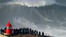 Warga menyaksikan aksi peselancar asal Jerman, Sebastian Steudtner saat menaklukan ombak selama sesi surfing ombak besar di Praia do Norte di Nazare, Portugal tengah (13/1). (AP Photo / Armando Franca)