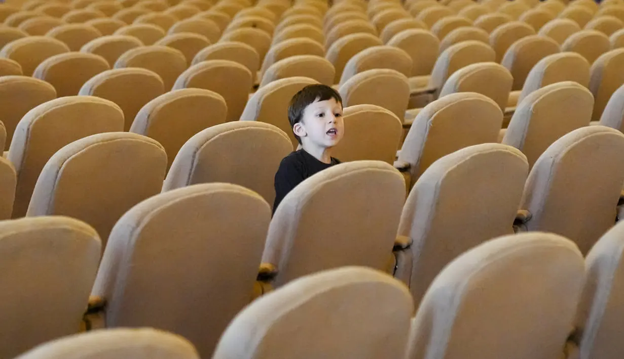 Seorang anak laki-laki mengintip dari balik kursi di aula konferensi Istana Parlemen pada Hari Anak Internasional di Bucharest, Rumania, Selasa (1/6/2021). Lebih dari 10 ribu anak-anak dan orang dewasa mengunjungi gedung era komunis yang juga dikenal House of the People. (AP Photo/Vadim Ghirda)