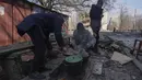 Para pria memasak makanan di sebuah jalan di Mariupol, Ukraina, Minggu, 13 Maret 2022. Rusia melancarkan invasi berskala besar ke Ukraina, salah satu negara tetangganya di sebelah barat daya. (AP Photo/Evgeniy Maloletka)