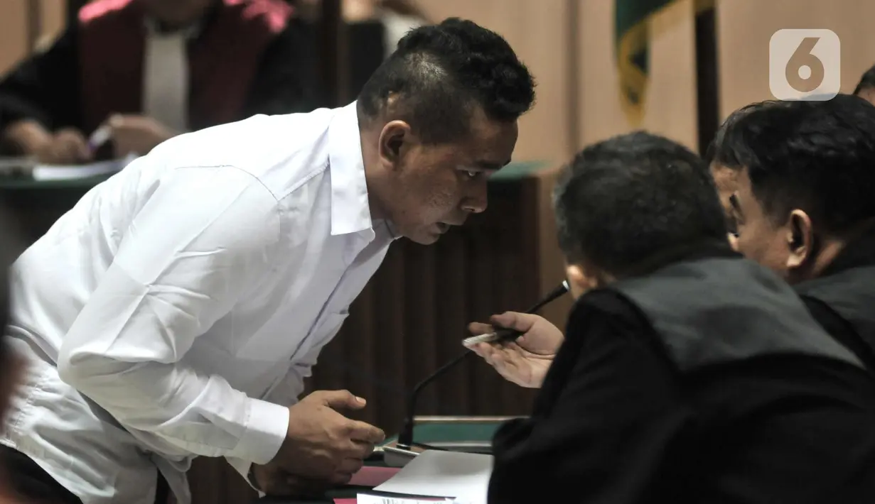 Salah satu terdakwa kasus penyiraman Novel Baswedan berdiskusi dengan kuasa hukum disela sidang perdana di Pengadilan Negeri Jakarta Utara, Kamis (19/3/2020). Dua terdakwa, yakni Ronny Bugis dan Rahmat Kadir Mahulete menjalani sidang dengan agenda pembacaan dakwaan. (merdeka.com/Iqbal Nugroho)