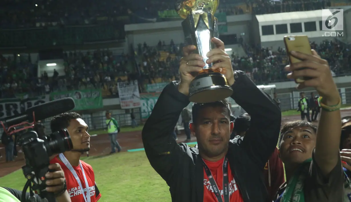 Pelatih Persebaya, Angel Alfredo Vera mengangkat piala usai menumbangkan PSMS Medan di Final Liga 2 Indonesia di Stadion GBLA, Bandung, Selasa (28/11). Persebaya unggul 3-2 atas PSMS Medan. (Liputan6.com/Helmi Fithriansyah)