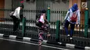 Sejumlah wanita memanjat pagar pembatas di Stasiun Cikini, Jakarta, Rabu, (20/12). Banyaknya penumpang yang mencari jalan pintas dengan melompat pagar untuk menuju akses pintu keluar menyebabkan kemacetan di kawasan stasiun. (Liputan6.com/Johan Tallo)