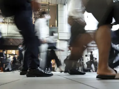 Komuter yang mengenakan masker berjalan di lorong selama jam sibuk di Stasiun Shinagawa, Tokyo, Jumat (1/10/2021). Pemerintah Jepang mencabut keadaan darurat di semua wilayah pada 1 Oktober 2021. (AP Photo/Eugene Hoshiko)