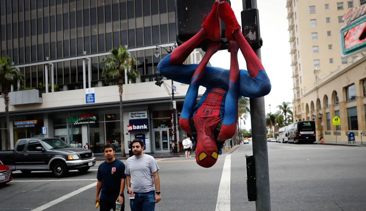 Rashad Rouse mengenakan kostum Spider-Man sembari bergelantungan di tiang lalu lintas untuk menarik perhatian turis di Hollywood Boulevard, Los Angeles, 25 Mei 2017. Pria 27 tahun itu bermimpi namanya akan masuk di Hollywood Walk of Fame (AP/Jae C. Hong)