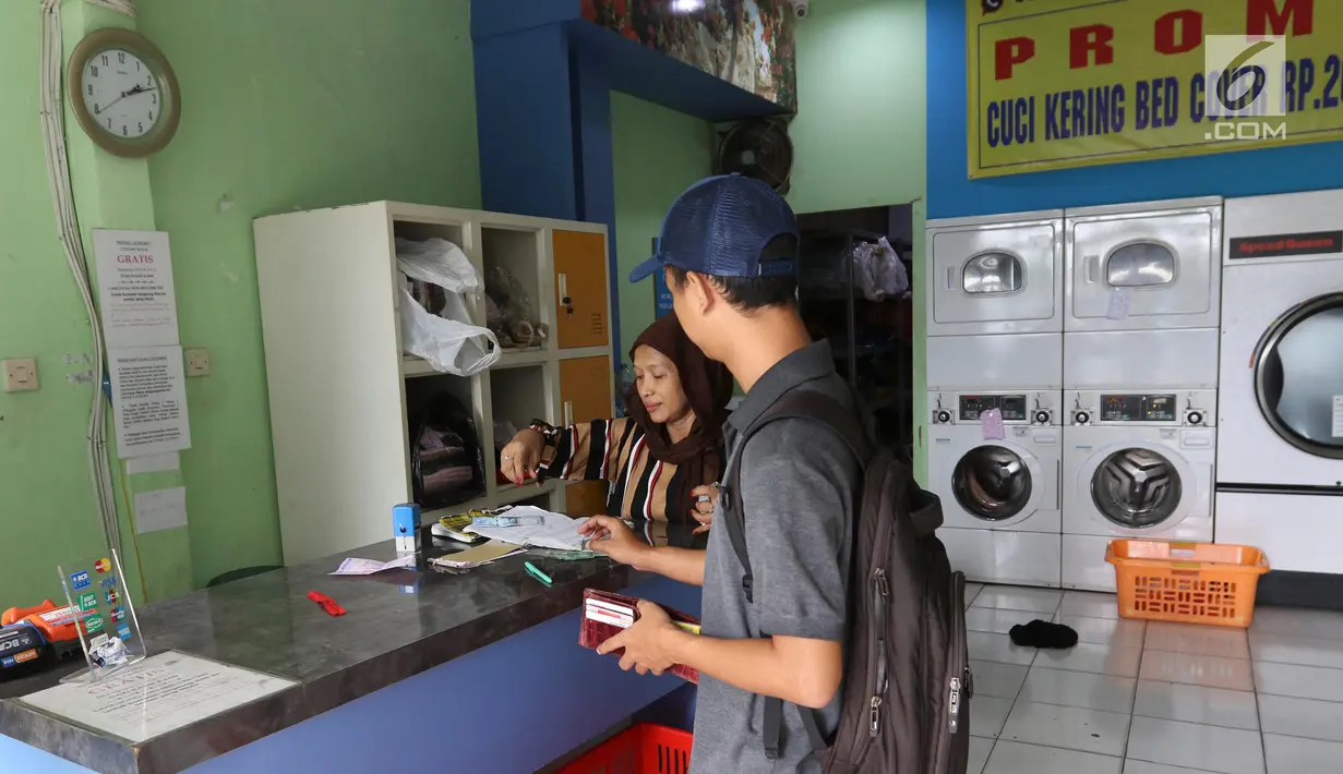 Pekerja melayani pelanggan di toko laundry di Jakarta, Rabu (20/6). Libur lebaran banyak jasa laundry kebanjiran order hingga 100 karena banyaknya para pembatu rumah tangga yang mudik lebaran. (Liputan6.com/Angga Yuniar)