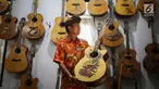 I Wayan Tuges melihat gitar yang telah diukirnya di workshop pembuatan gitar berlabel Blueberry di Jalan Baruna No. 5 Guwang, Sukowati, Bali, Senin (15/10). Gitar-gitar produksinya itu dibanderol seharga puluhan juta rupiah. (Liputan6.com/Angga Yuniar)