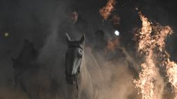 Sejumlah penunggang kuda melompati api unggun di desa San Bartolome de Pinares, Spanyol (16/1). Ritual ini merupakan cara unik menolak bala dan bahaya sepanjang 2018. (AFP Photo/Gabriel Bouys)