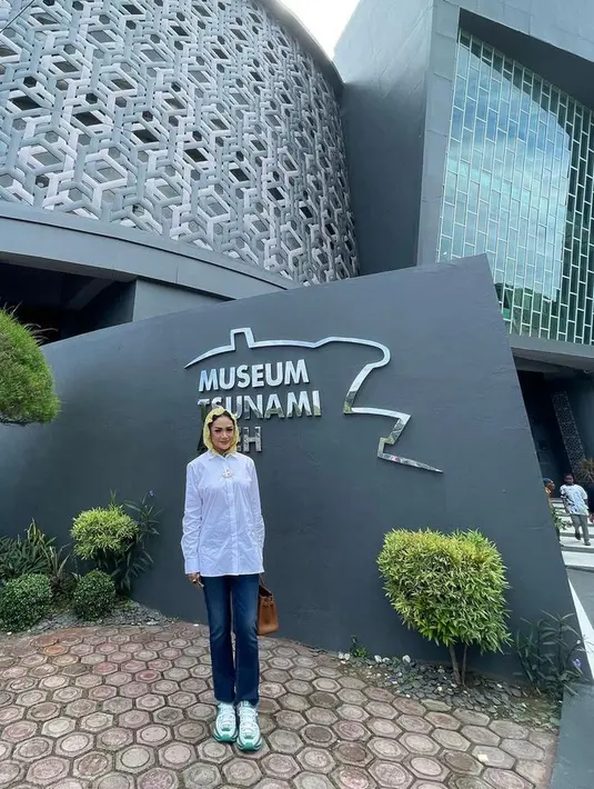 Mengunjungi Museum Tsunami, Krisdayanti tampil kasual memadukan kemeja putih, celana jeans, dan penutup kepala warna kuning. @krisdayantilemos.