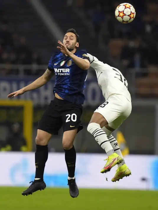 Gelandang Inter Milan Hakan Calhanoglu dan gelandang Shakhtar Donetsk Pedrinho melompat saat berebut bola pada matchday 5 Grup D Liga Champions 2021/2022 di Stadion Giuseppe Meazza, Kamis (25/11/2021) dini hari WIB. Inter Milan menundukkan Shakhtar Donetsk 2-0. (AP Photo/Luca Bruno)
