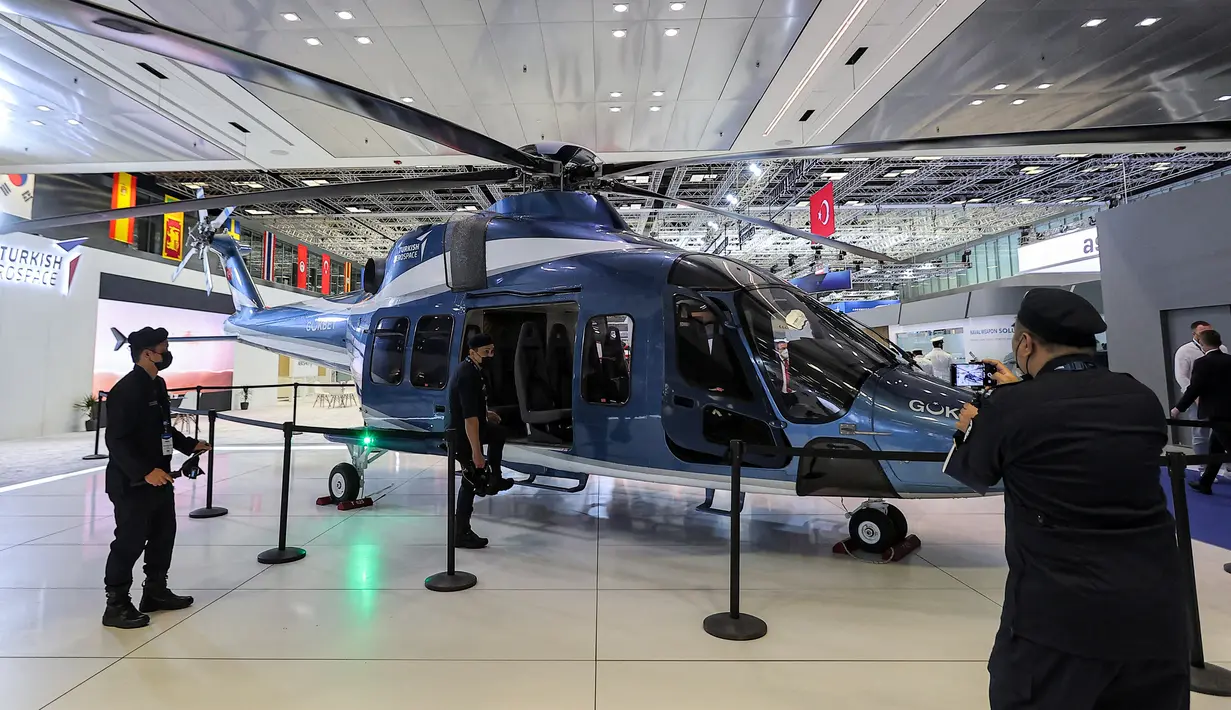 Para peserta berpose untuk difoto dengan helikopter transportasi/utilitas Turkish Aerospace Industries T625 Gökbey yang dipamerkan pada Pameran Pertahanan Maritim Internasional Doha atau Doha International Maritime Defense Exhibition (DIMDEX) di Doha, Qatar, 21 Maret 2022. (KARIM JAAFAR/AFP)